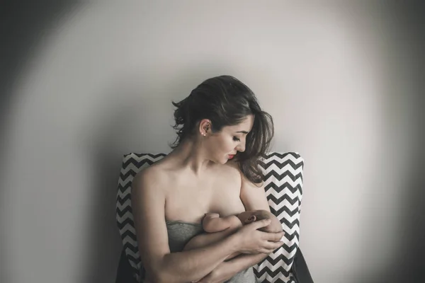 Madre joven sosteniendo a su hijo recién nacido. Mamá amamantando bebé. —  Fotos de Stock