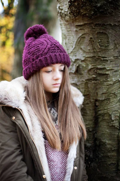 Teini-ikäinen tyttö yllään villahattu seisoo vieressä puu — kuvapankkivalokuva