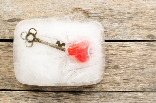 Серце і ключ заморожені в блоці льоду на старих дошках — стокове фото