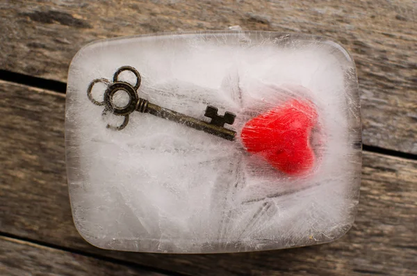 Сердце и ключ застыли в глыбе льда на старых досках — стоковое фото