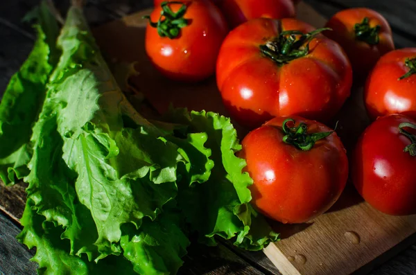 Tomates maduros em uma tábua de corte — Fotografia de Stock