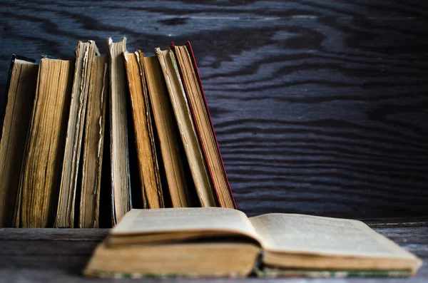 Tahta bir masanın üzerinde bir yığın eski kitap.