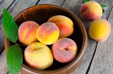 Ahşap arka plan üzerinde Şeftalilerin ahşap kase