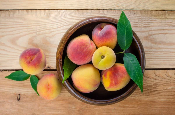 Ahşap arka plan üzerinde Şeftalilerin ahşap kase