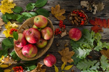 Sonbahar yaprakları ve eski kurulları bir arka plan üzerinde hasır sepet elma