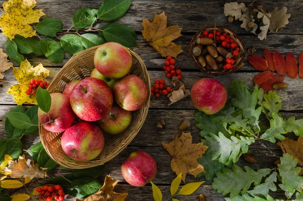 Sonbahar yaprakları ve eski kurulları bir arka plan üzerinde hasır sepet elma