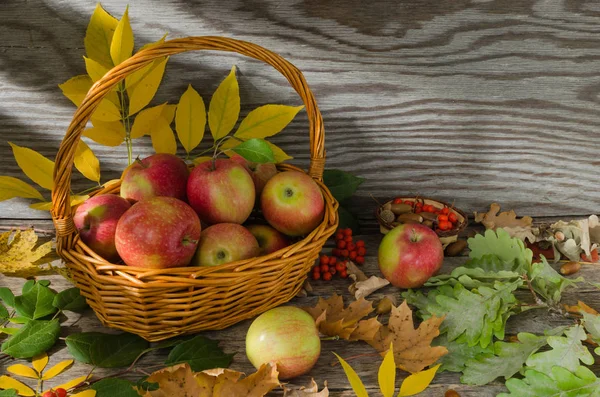Sonbahar yaprakları ve eski kurulları bir arka plan üzerinde hasır sepet elma