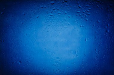 Mavi bir arka plan üzerinde camına yağmur damlaları
