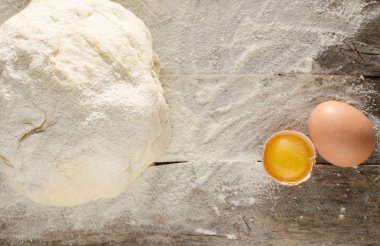Hamur yoğrulur ve ahşap bir masa üzerinde yumurta un ile silkeledi