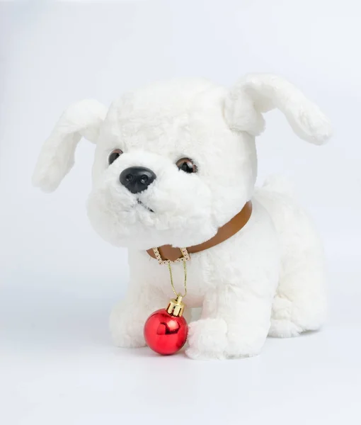 Brinquedo de cachorro branco em um fundo leve com decorações de Natal no colarinho — Fotografia de Stock