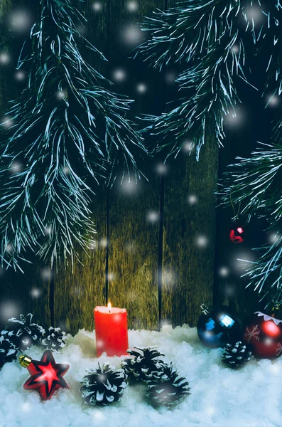 クリスマスの飾り、赤いろうそくと木製の背景と木の枝の雪の中のおもちゃ — ストック写真