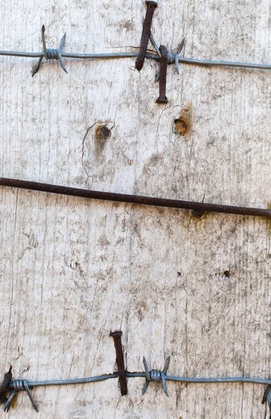 带刺的铁丝钉在有锈迹斑斑的木板上 — 图库照片