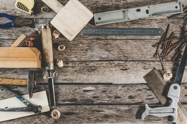 Плотник инструменты на деревянной скамейке, плоскость, зубило, молоток, лента мера, молоток, щипцы, плоскогубцы, уровень, ногти и пила — стоковое фото