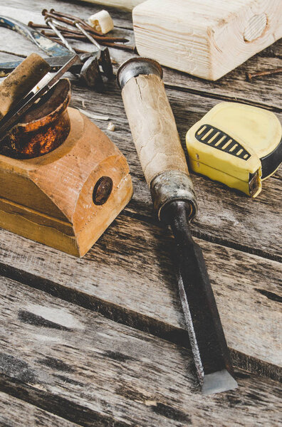 The carpenter tools on wooden bench, plane, chisel,mallet, tape measure, tongs, nails and a saw