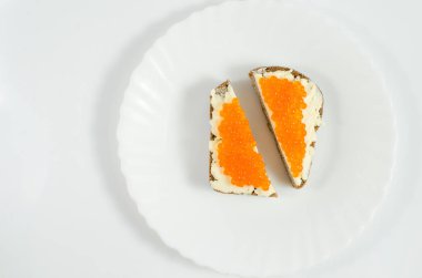 Siyah çavdar ekmeği bir parça tereyağı ve kırmızı havyar ile yağlanmış bir beyaz tabakta kesti