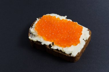 Bir parça siyah ekmek üzerinde kırmızı havyar ve tereyağı sürülür