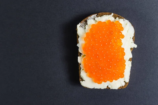 Red caviar and butter smeared on a piece of black bread — Stock Photo, Image