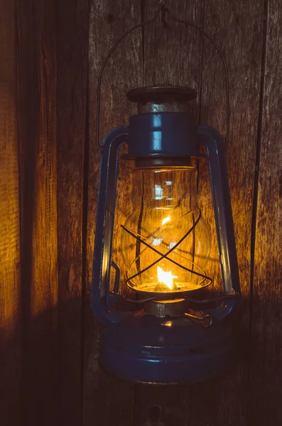 Kerosene lamp illuminates the old wooden wall