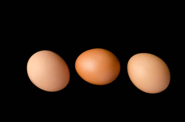 Three brown, chicken eggs black background. — Stock Photo, Image