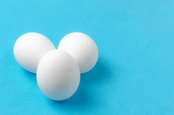 White chicken eggs on blue background. — Stock Photo, Image