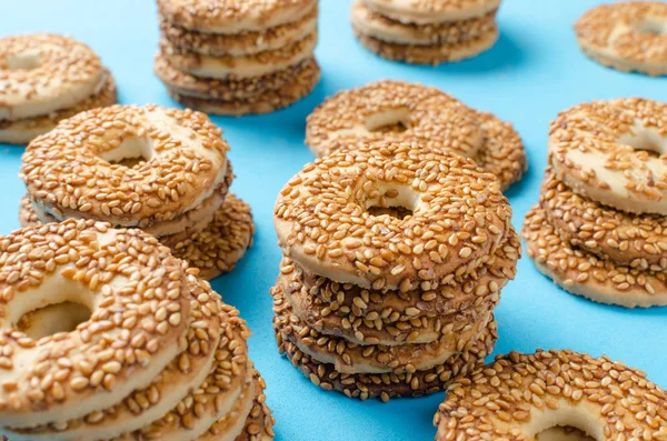 Round cookies with sesame seeds on a bright blue background.