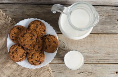 Bisküvi, bir sürahi ve bir bardak süt çuval bezi, eski tablo üzerinde. Üstten Görünüm.