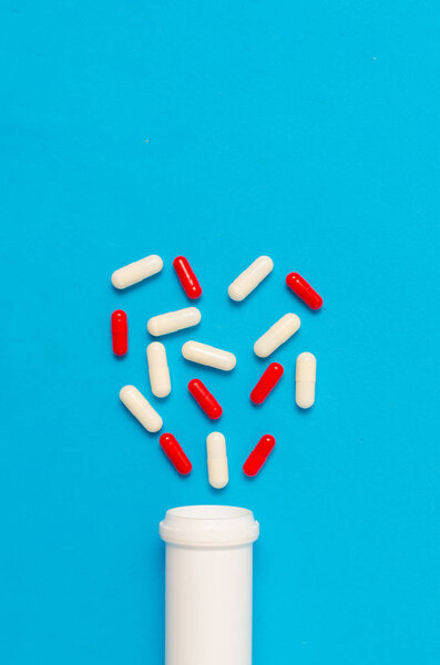 Variety of tablets and pills.Pharmaceuticals and antibiotics heart-shaped bottle on blue background.