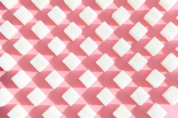 Açúcar refinado sobre fundo rosado.Cubos de açúcar doce e branco em forma geométrica. Sombras duras . — Fotografia de Stock
