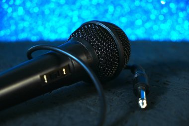 Siyah mikrofon siyah ahşap zemine düştü. Parlak mavi boke. Şarkı söylemek ve karaoke yapmak için müzik aleti..