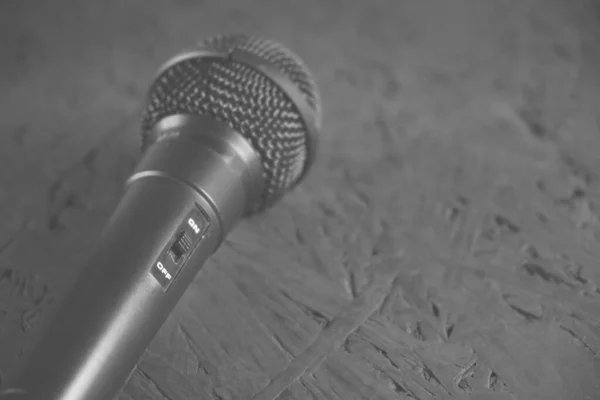 Schwarzes Mikrofon fiel auf den schwarzen Holzboden. Musikinstrument zum Singen und Karaoke. — Stockfoto