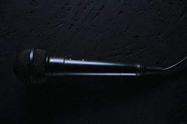Micrófono negro cayó al suelo de madera negra.Instrumento musical para cantar y karaoke . —  Fotos de Stock