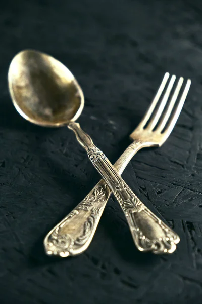 Old Cutlery spoon and fork on black wooden table.