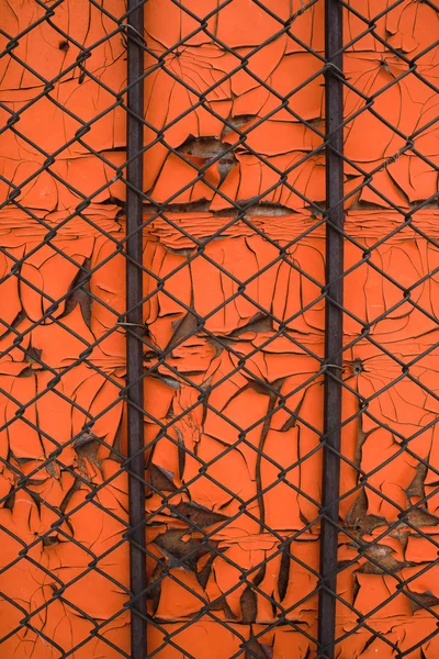 Orangefarbener Hintergrund aus alter abblätternder Farbe und Gitternetz. — Stockfoto