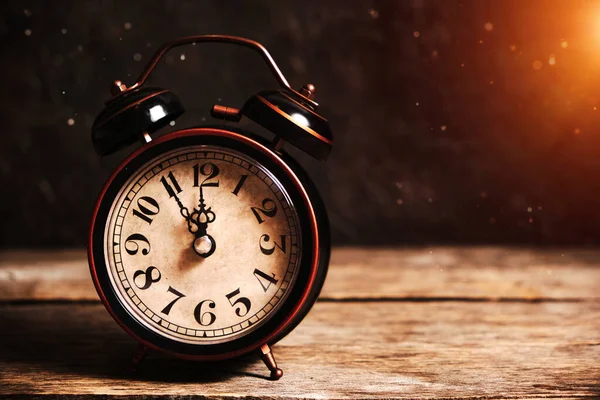 Un viejo reloj despertador vintage sobre una mesa de madera con polvo asentándose sobre un fondo de luz solar . —  Fotos de Stock