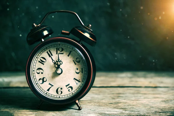 An old vintage alarm clock on a wooden table with dust settling on a background of sunlight. — Stock Photo, Image