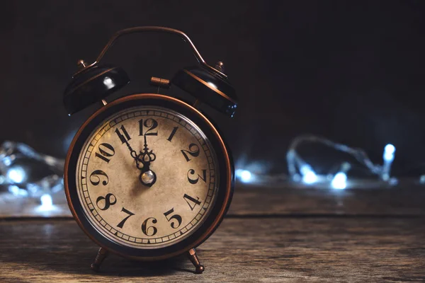 Antiguo, retro, reloj despertador vintage en mesa de madera sobre fondo de guirnalda de Navidad . —  Fotos de Stock