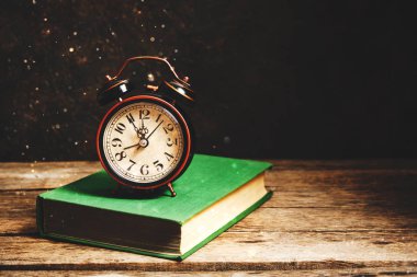 Kırsal kesimde yeşil kitaptaki eski alarm saati.