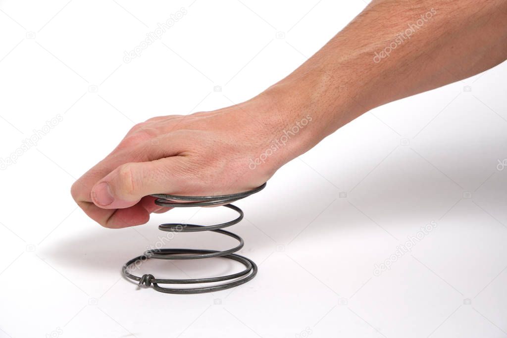 A man's hand presses on a spring, on a white background.Exert pressure.