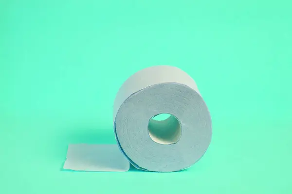 Rolo de papel higiênico em um fundo turquesa . — Fotografia de Stock