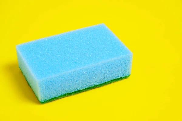 Blue sponge for washing dishes on a yellow background. — Stock Photo, Image