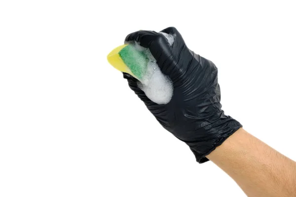 La mano del hombre en un guante negro agarra una esponja de espuma para lavar los platos con espuma . —  Fotos de Stock