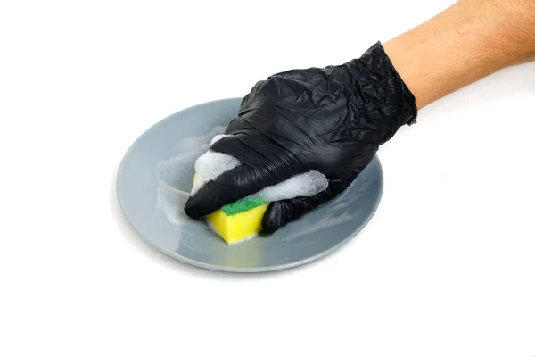 Mann in schwarzen Handschuhen wäscht Teller mit Schaumschwamm auf weißem Hintergrund. — Stockfoto