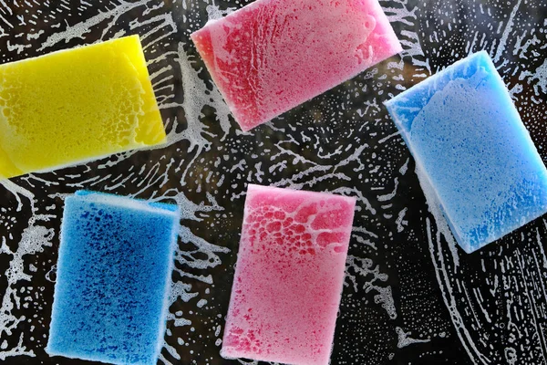 Multi-colored sponge for washing dishes on the glass with liquid and foam for washing dishes. — 스톡 사진