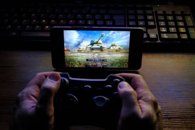 Kostanay, Kazakhstan, February 12, 2020.Joystick and mobile phone with the logo of the popular game World of Tanks, from Wargaming.