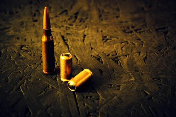 Balas de uma metralhadora e uma pistola em um fundo escuro . — Fotografia de Stock