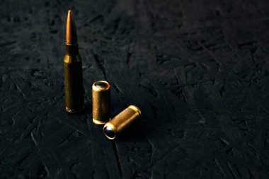 Makineli tüfekten çıkan kurşunlar ve karanlık bir arka planda bir tabanca..