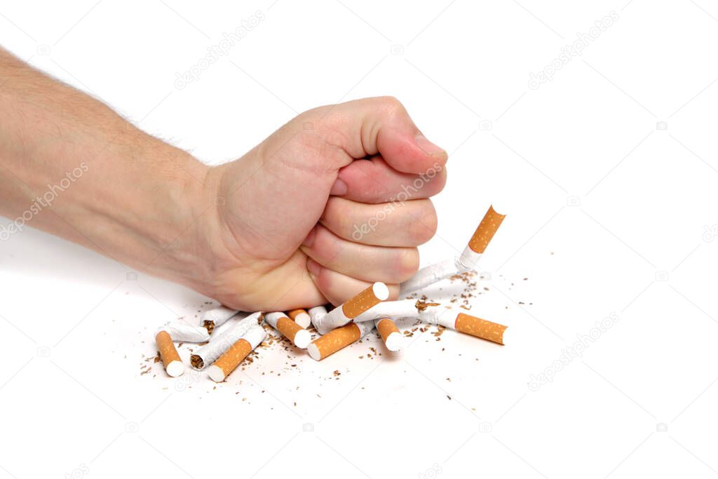 Man crushes cigarettes with his fist refusing to smoke.On white background