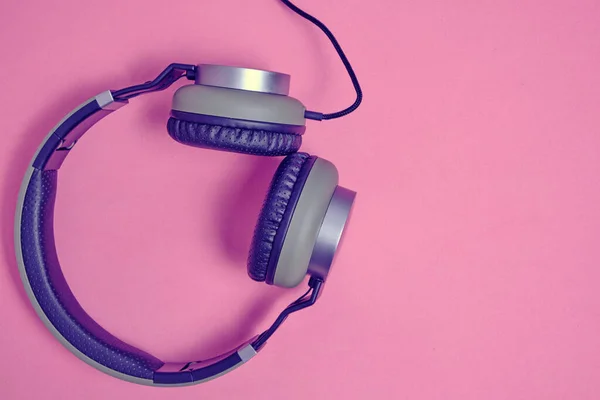 Wired headphones in khaki on a pink background.Vintage and retro