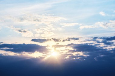 Batan güneş bulutların arkasında ve ışık huzmeleri bulutların arasından kırılıyor.