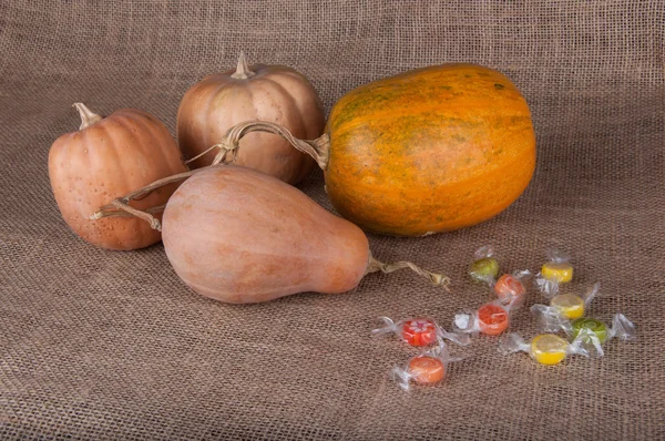 Quatre citrouilles et bonbons multicolores posés sur le sac — Photo